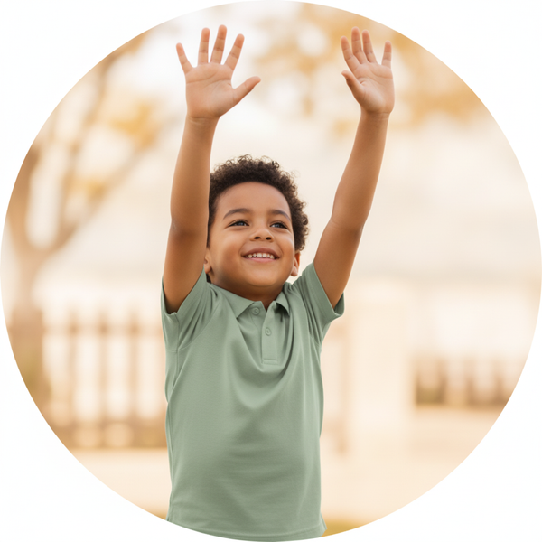 A child in a sage green Golfino Polo stretches arms up, demonstrating flexible movement against a blurred, warm-toned backgro